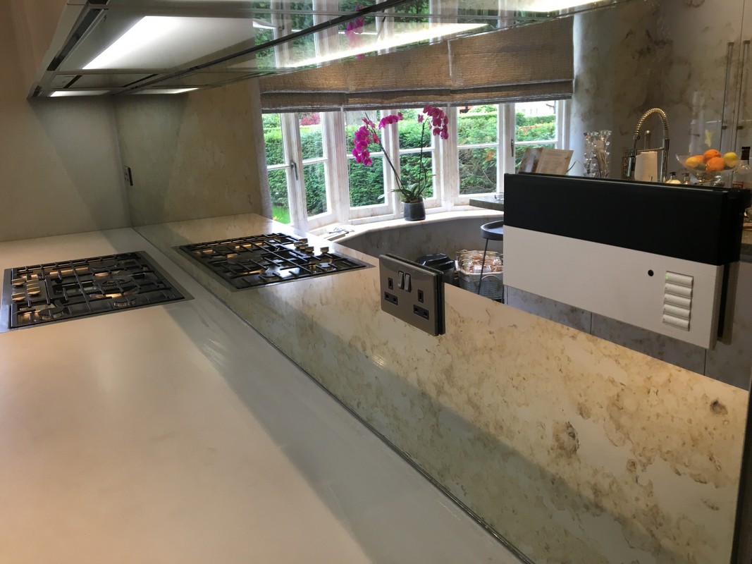 Clear glass splashback protecting marble walls in luxury kitchen